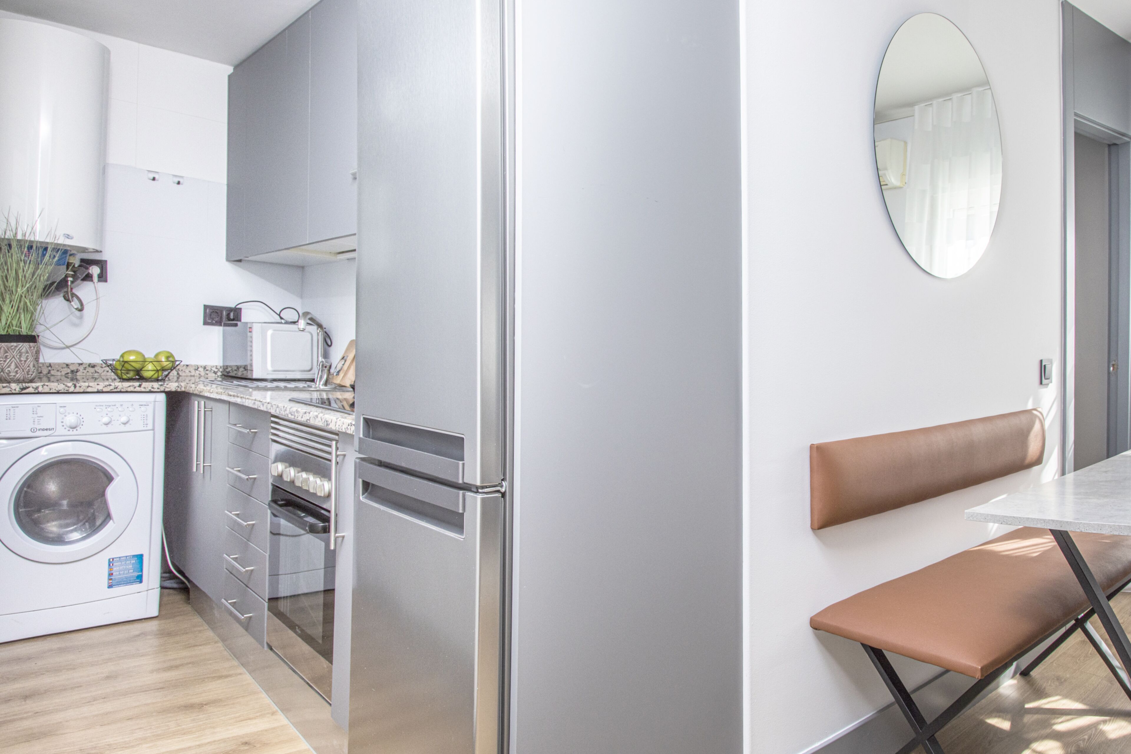 A modern kitchen with a built-in washing machine, oven, and microwave.