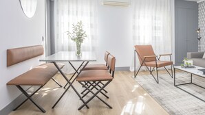 A modern living room with a sofa, a coffee table, and a dining area with a table and chairs. - Incredible 2 Bedroom Apartment at El Rastro (Madrid)