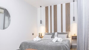 A modern bedroom with a large bed, a round mirror, and a wooden accent wall. - Incredible 2 Bedroom Apartment at El Rastro (Madrid)