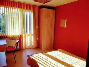 Una habitación con cama, escritorio, silla, armario y radiador.