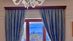 Quarto com vista para a cidade através de uma porta de vidro e cortinas azuis.