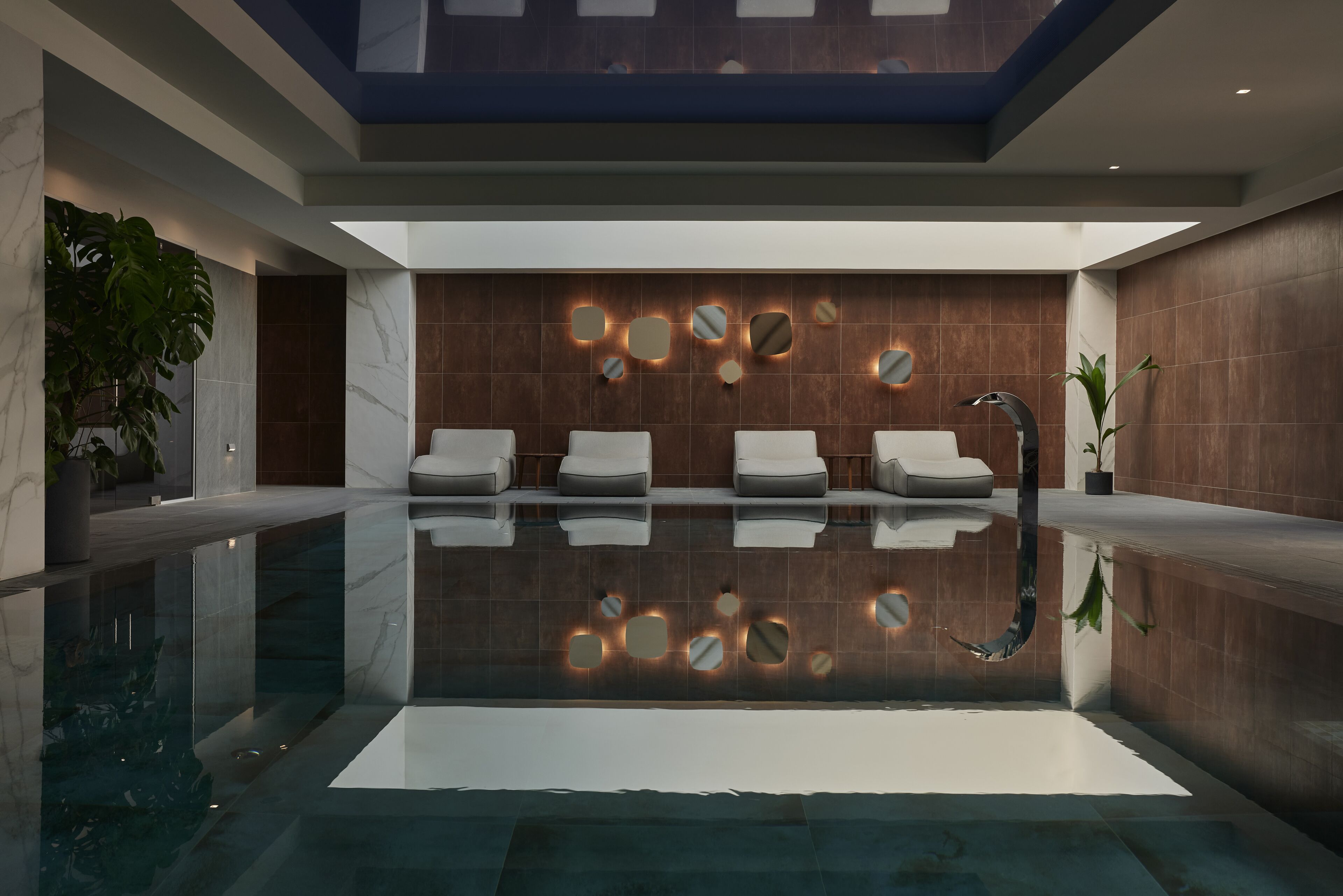 Un área interior de piscina moderna con vista despejada, sillones de descanso y un diseño de pared único.