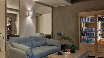 Una sala de estar moderna con un sofá azul claro, una mesa de centro de madera y un armario de vidrio con artículos de aseo.