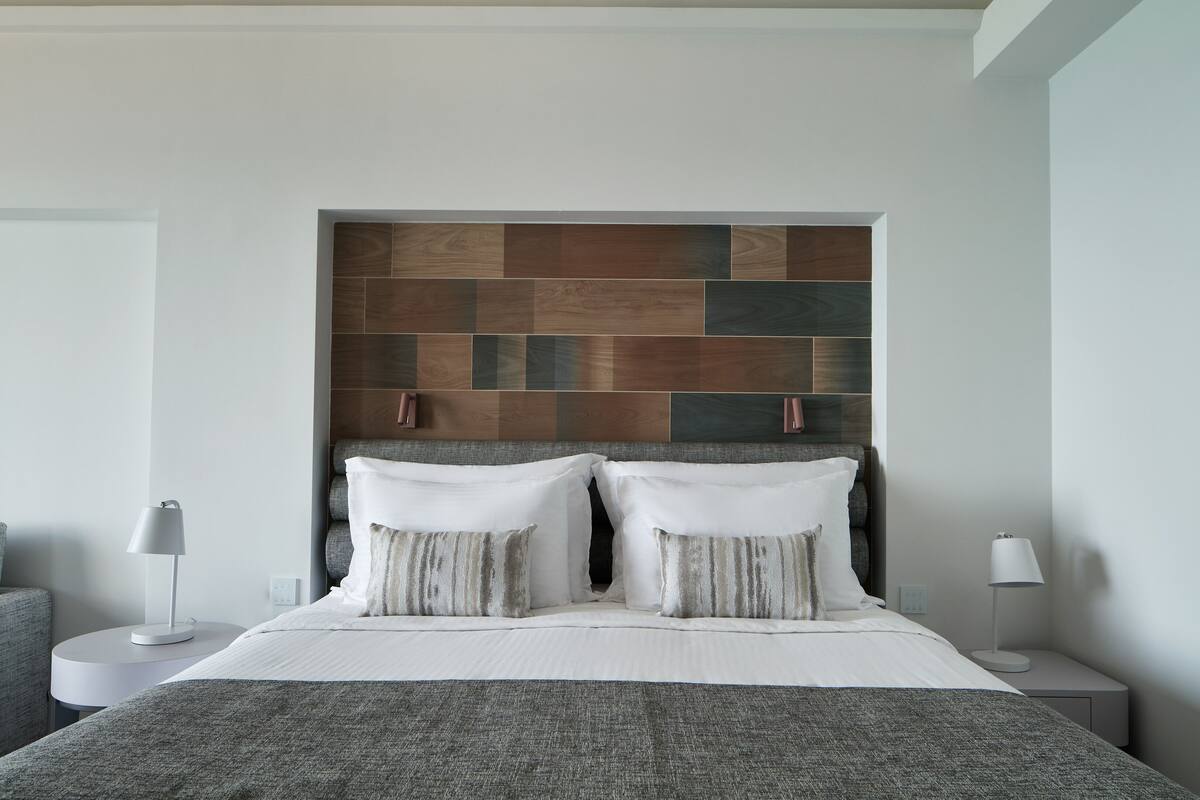A modern bedroom with a large bed, two bedside tables, and a decorative wall panel above the bed.