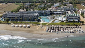 A resort with multiple buildings, a large swimming pool, and a beach area with sun loungers. - AMIRA LUXURY RESORT & SPA (Rethymno)