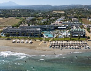 A resort with multiple buildings, a large swimming pool, and a beach area with sun loungers. - AMIRA LUXURY RESORT & SPA (Rethymno)