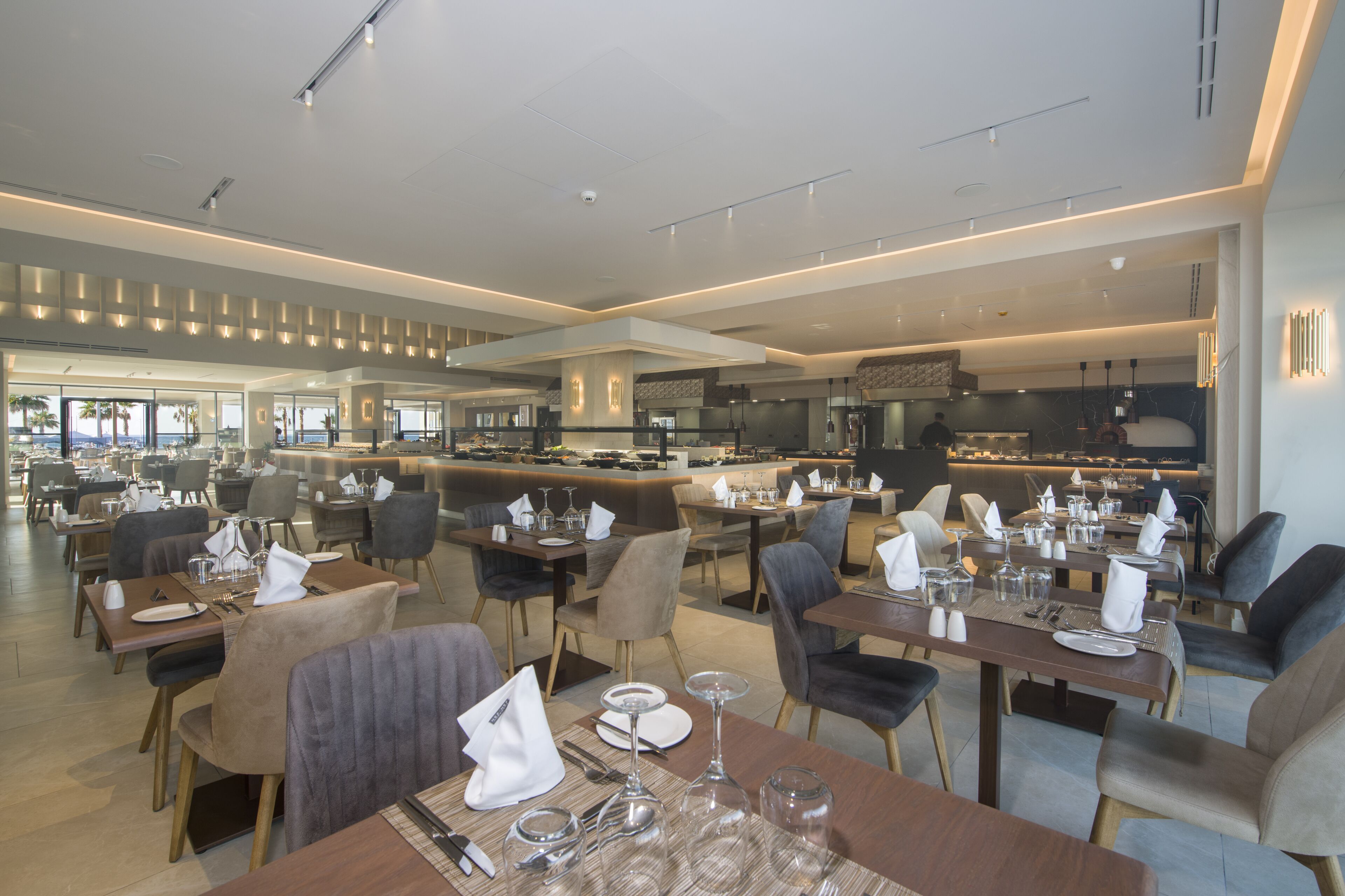 A modern restaurant with multiple dining areas, each equipped with tables, chairs, and glassware.