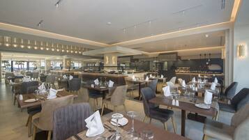 A modern restaurant with multiple dining areas, each equipped with tables, chairs, and glassware.