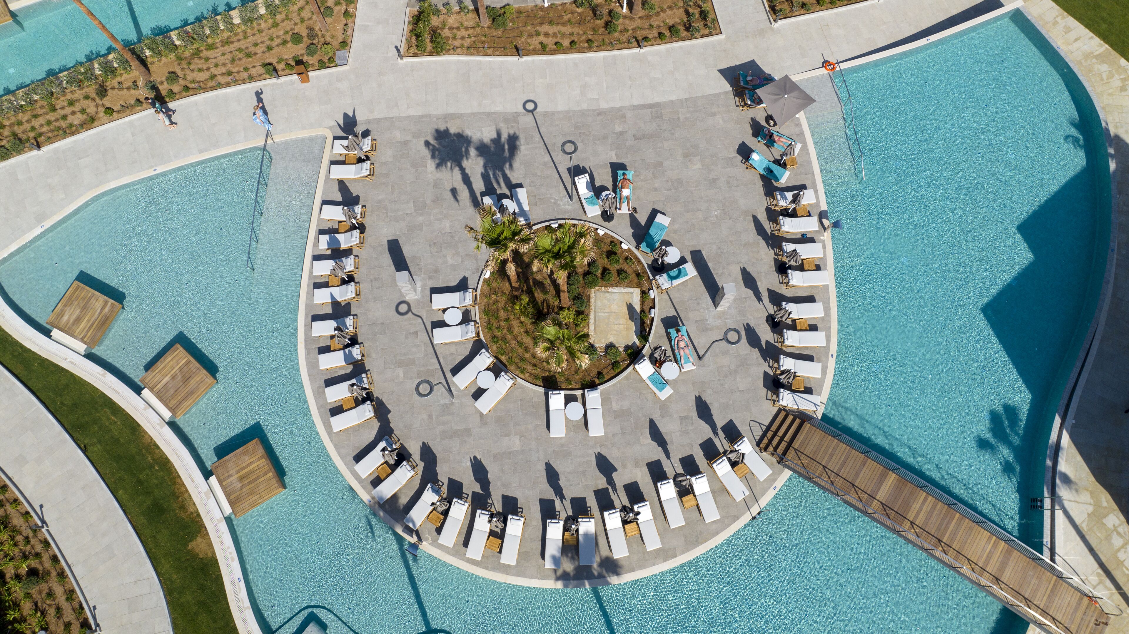 An aerial view of a circular pool area with lounge chairs and a central garden.