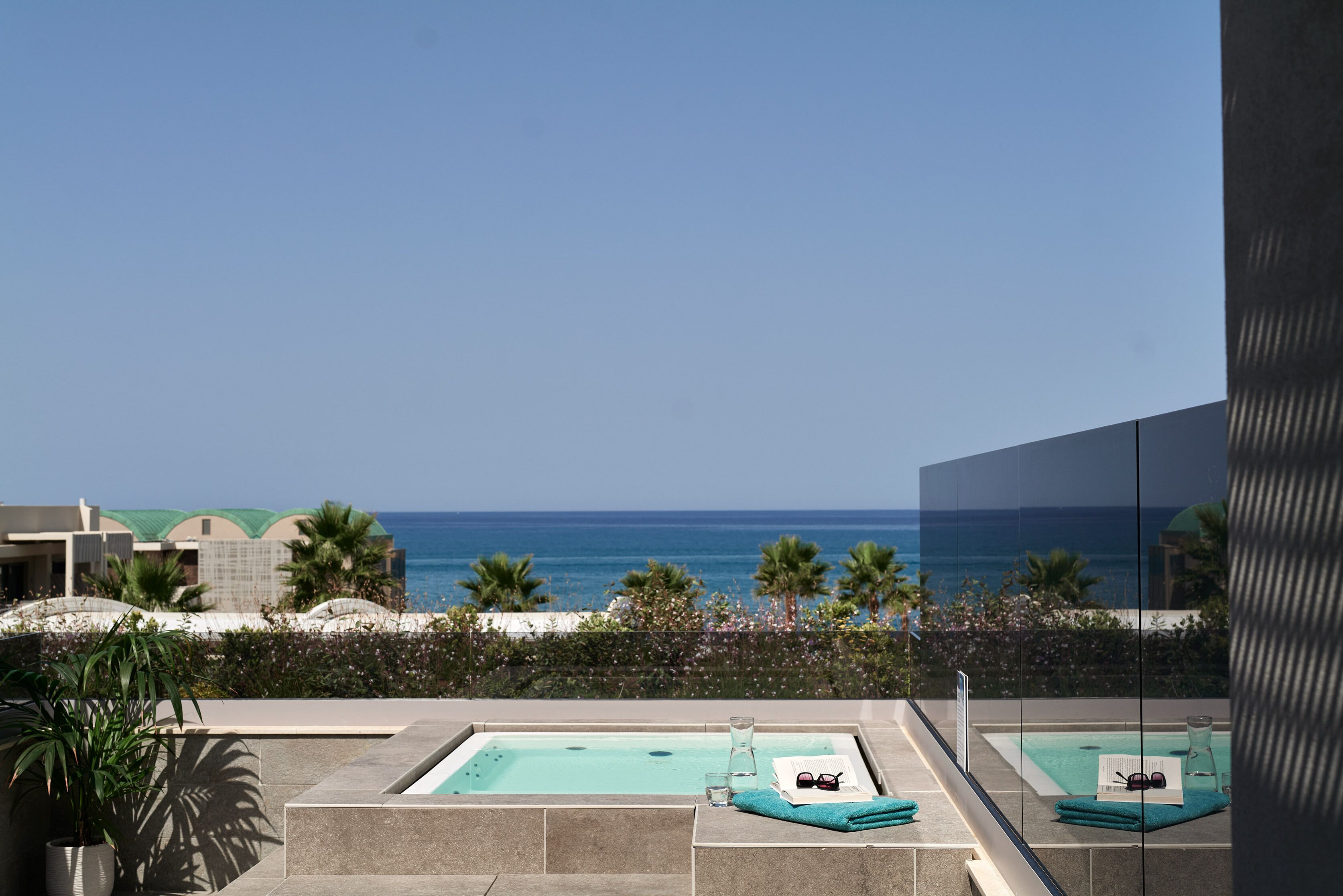 A modern pool area with clear blue water, a glass enclosure, and a view of the ocean.