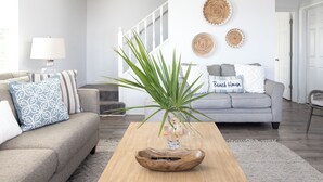 A living room with a grey sofa, a wooden coffee table, and a staircase. - Bayfront, kayaks, private dock, 5 minute walk to the Gulf (Gulf Shores)