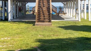 A two-story house with a wooden deck and a staircase leading to the upper level. - Bayfront, kayaks, private dock, 5 minute walk to the Gulf (Gulf Shores)