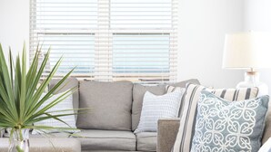A living room with a grey sofa, patterned pillows, a wooden coffee table, and a potted plant. - Bayfront, kayaks, private dock, 5 minute walk to the Gulf (Gulf Shores)