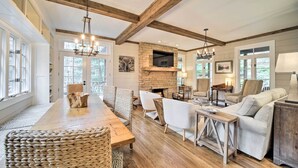 A spacious living room with a wooden dining table, comfortable seating, a fireplace, and a television. - Beautiful Trillium Home Next to Waterfall! (Cashiers)
