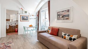 Ein modernes Wohnzimmer mit einer Couch, einem Esstisch und einer Küchenzeile.