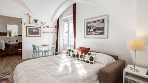 Ein Schlafzimmer mit Bett, Schreibtisch, Stuhl, Lampe und Kunstwerken an den Wänden.