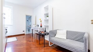 Ein modernes Wohnzimmer mit einem grauen Sofa, einem Essbereich mit Tisch und Stühlen sowie einer Küchenzeile mit Spüle und Arbeitsplatte.