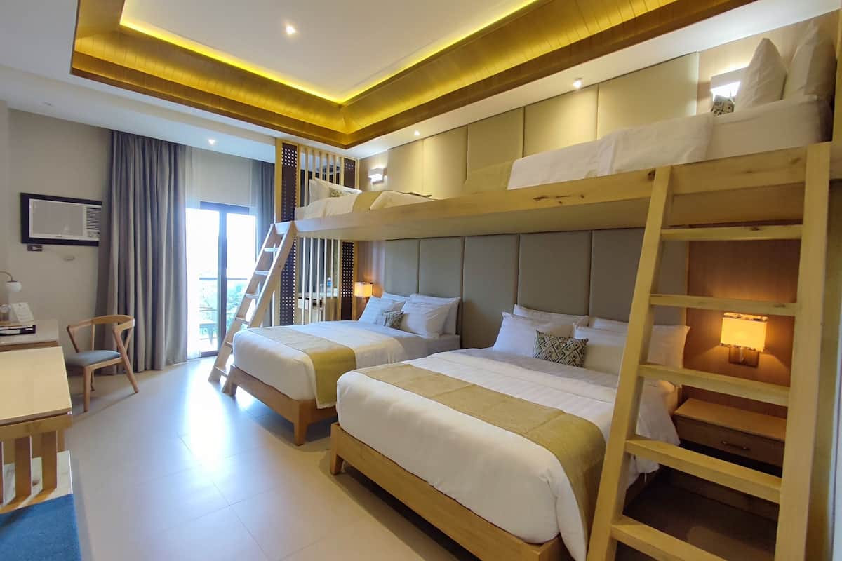 A hotel room with two beds, a desk, and a chair. There is a staircase leading to an upper level.