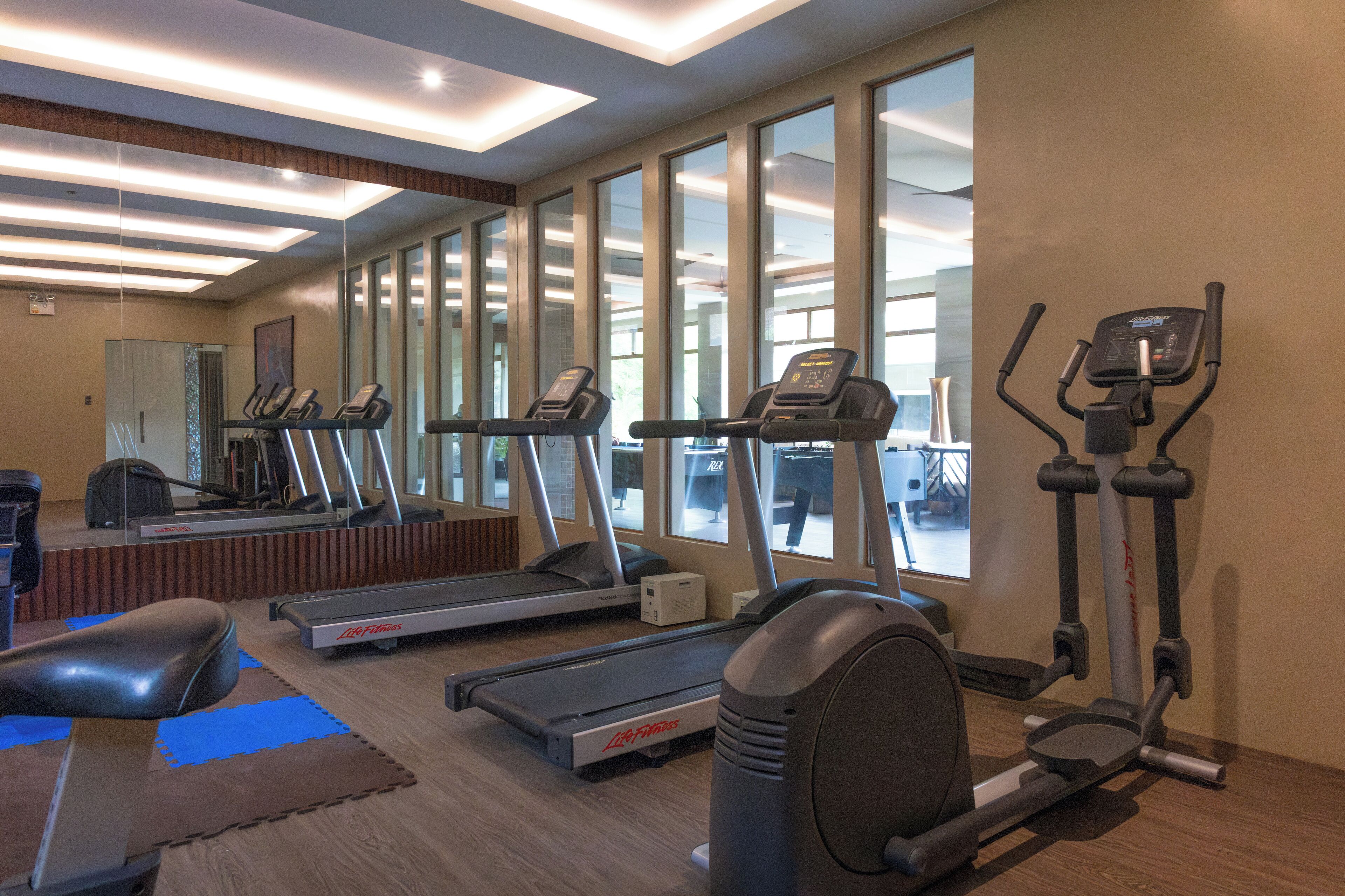 Un gimnasio con cintas de correr, elípticas y una bicicleta estática.
