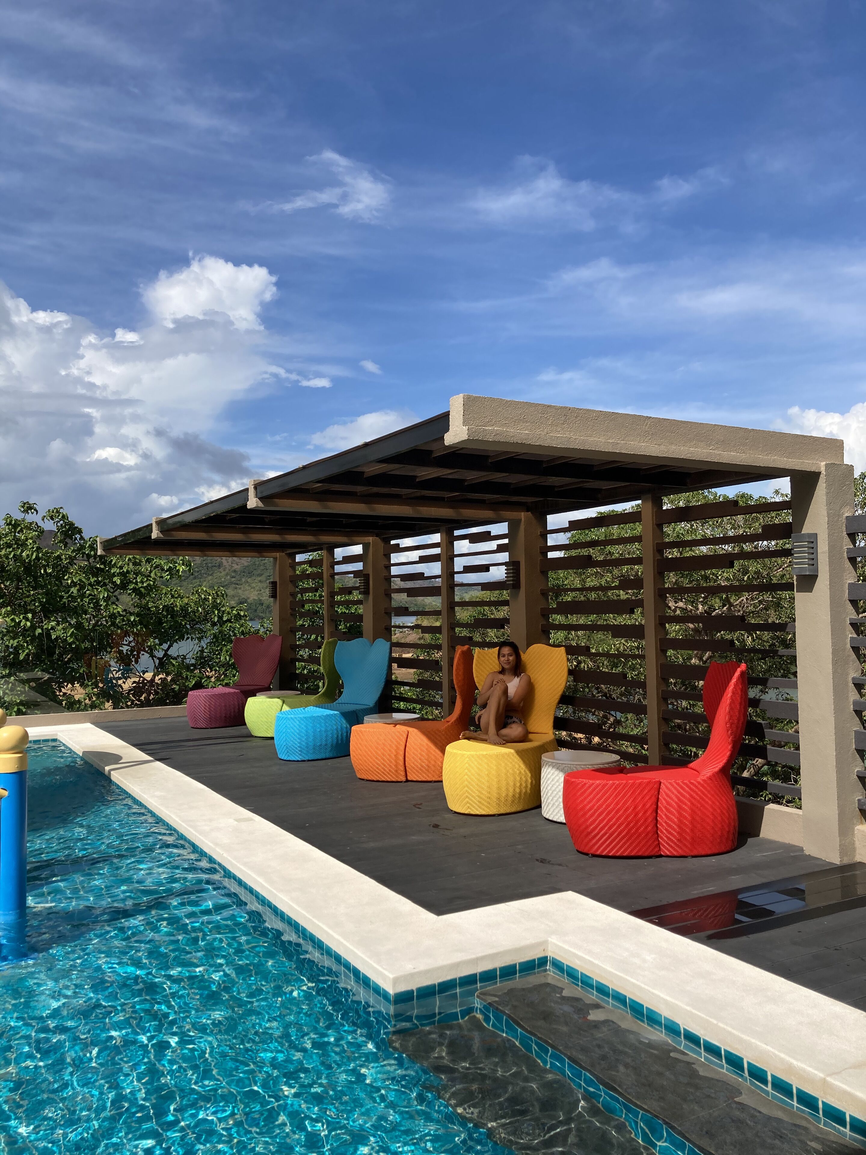 Zona de piscina con mobiliario de colores y una estructura de pérgola.