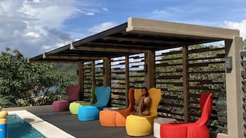 Zona de piscina con mobiliario de colores y una estructura de pérgola.