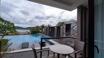 Relax by the pool surrounded by lush greenery and distant hills.