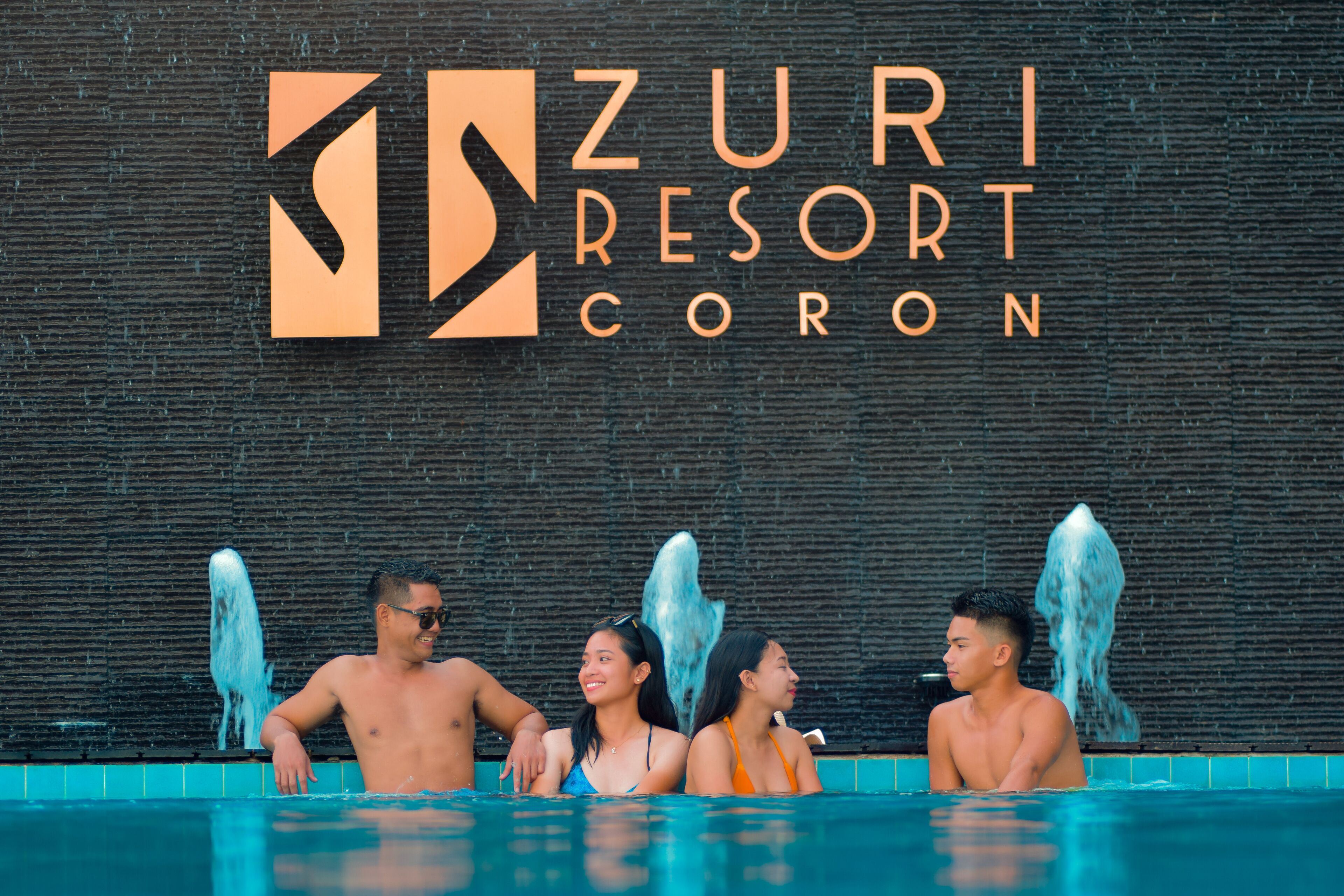 Una piscina con un cartel que dice "ZURI RESORT CORON" al fondo.