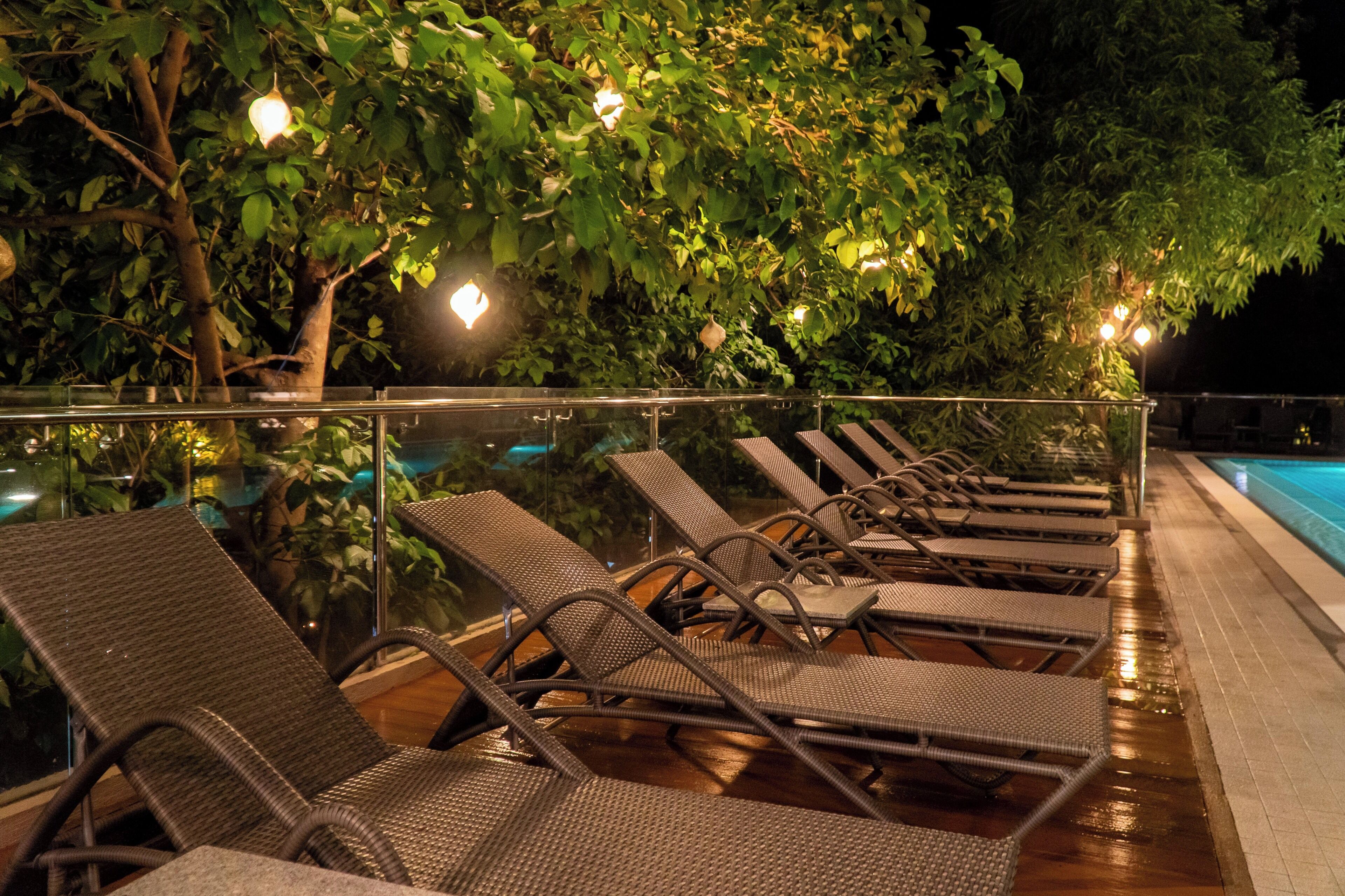 A poolside area with lounge chairs and a glass railing.
