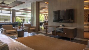 Una sala de estar moderna con mesa de billar, asientos cómodos, televisor de pantalla plana y un amplio ventanal con vistas al exterior.