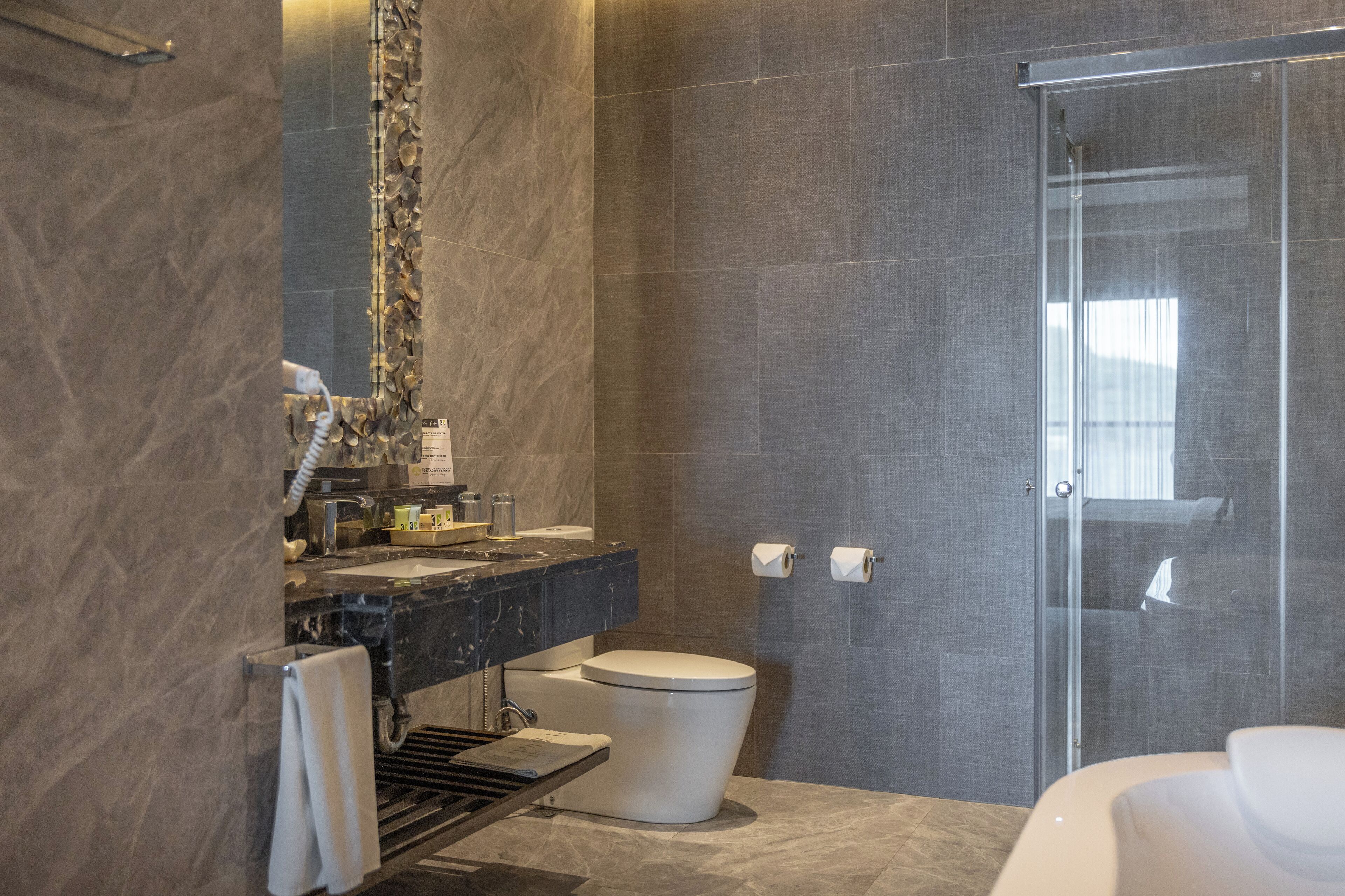 A modern bathroom with a marble sink, a toilet, and a glass shower enclosure.