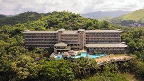 Un gran hotel con varias edificaciones, una piscina y exuberante vegetación a su alrededor.