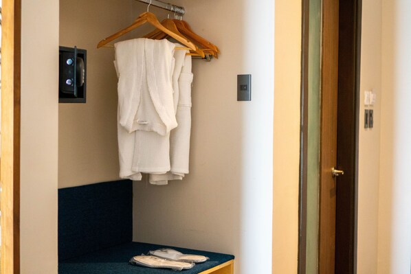 Une chambre avec un lit, un banc avec des chaussons et un porte-serviettes sur lequel est posée une serviette blanche.