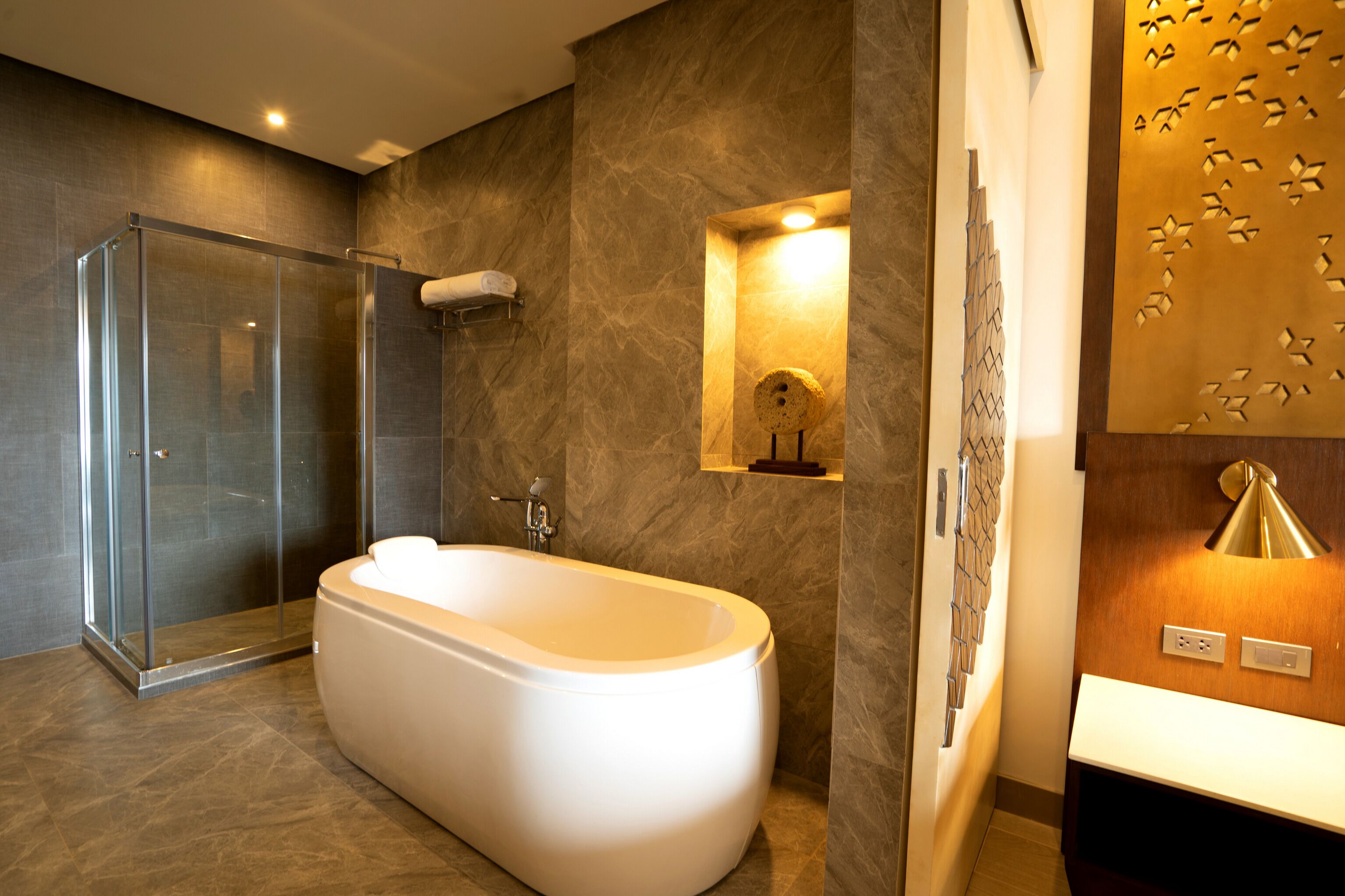 A modern bathroom with a freestanding bathtub, a glass shower enclosure, and a decorative wall panel.