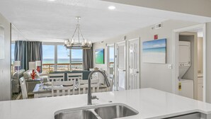 Una cocina moderna con una isla grande, pileta de acero inoxidable y vista al océano.