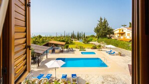 A pool area with two pools, lounge chairs, and umbrellas. - Villa Xenios Dias in Argaka (Argaka)
