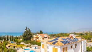 A coastal property with a swimming pool, solar panels, and a view of the sea. - Villa Xenios Dias in Argaka (Argaka)