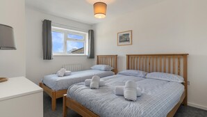 Ein Hotelzimmer mit zwei Holzbett, einem Schreibtisch, einem Vorhangfenster und einer Wandlampe.