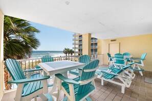 Enjoy the ocean view from this balcony with comfortable seating and a table.