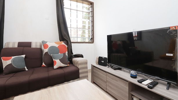 A modern living room with a brown sofa, patterned cushions, a flat-screen TV, and a wooden coffee table.