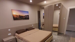 Une chambre moderne avec un grand lit, des tables de chevet, une petite table et un tableau accroché au mur.