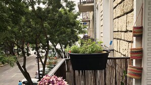 A balcony with a table, a hanging basket, and a potted plant. - Beautiful family apartment at the foot of Montmartre (Paris)