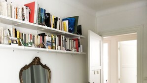A bedroom with a bed, a dresser, a vanity with a mirror, and a bookshelf filled with books. - Beautiful family apartment at the foot of Montmartre (Paris)