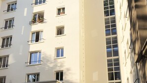 A multi-story building with a flat facade, large windows, and a central entrance with a door and a mailbox. - Beautiful family apartment at the foot of Montmartre (Paris)