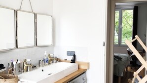 A modern kitchen with a built-in washing machine, a wooden countertop, and a large window. - Beautiful family apartment at the foot of Montmartre (Paris)