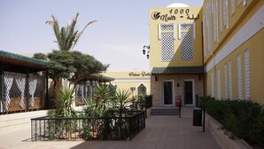 Ein Gebäude mit einem Schild, auf dem die Schriftzüge „1000“ und „Nuits“ in arabischer Schrift stehen, was auf ein Hotel oder Resort hindeutet.