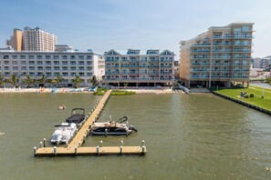 Ein Hotel direkt am Wasser mit mehreren Balkonen, einer Bootsanlegestelle und einem Strandabschnitt.