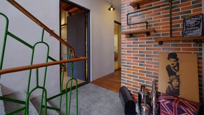 A staircase with green railings, a brick wall with shelves, and a poster. - Japan Travel Accommodation (Tainan)