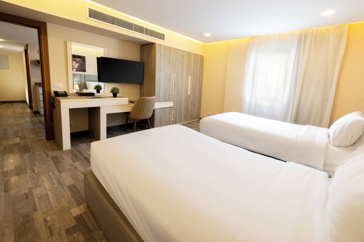 Una habitación de hotel con cama, escritorio, silla y televisor.