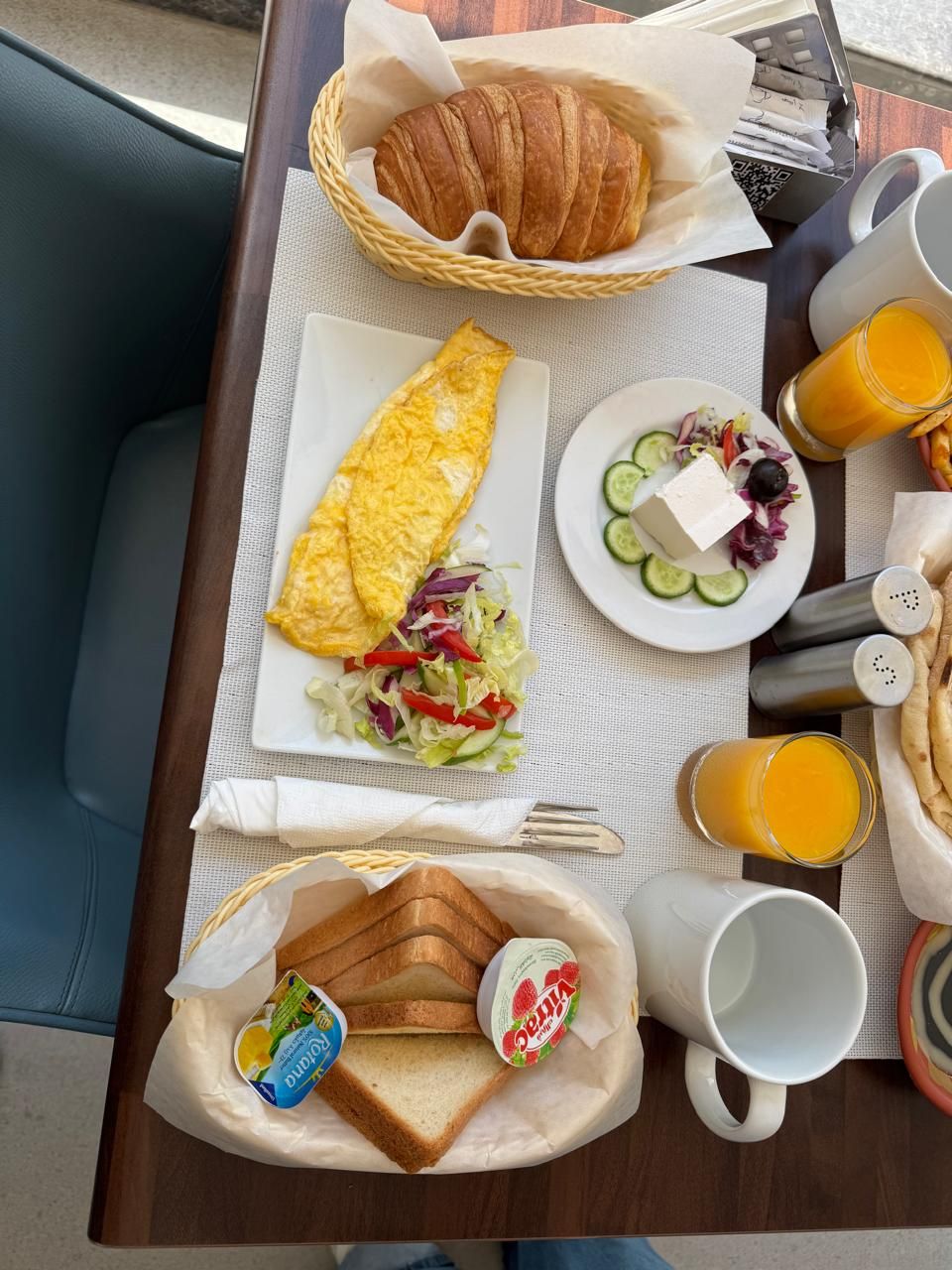 Bandeja de desayuno con tortilla, croissant, ensalada, yogur y jugo.
