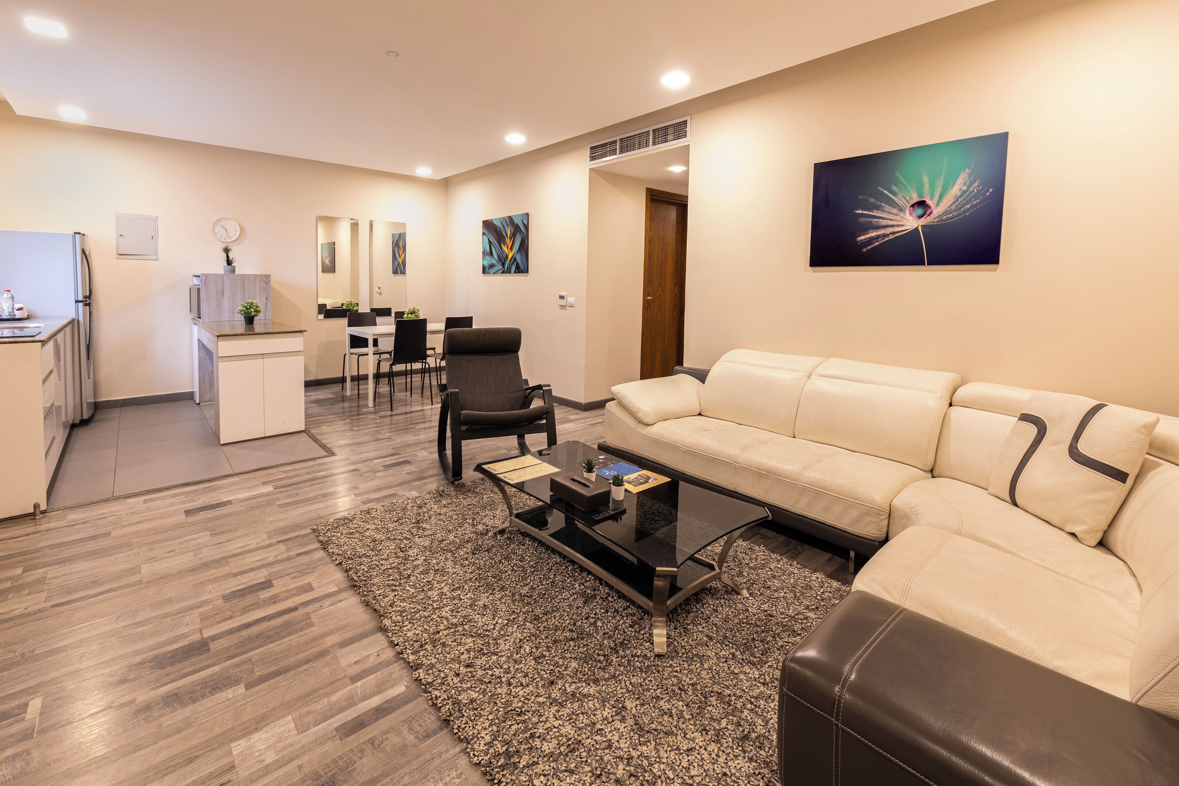 A modern living room with a sofa, coffee table, and a dining area with chairs and a table.